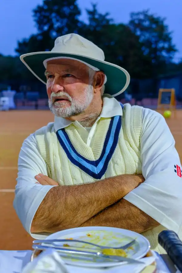Deelnemer in cricketsweater aan tafel na het diner